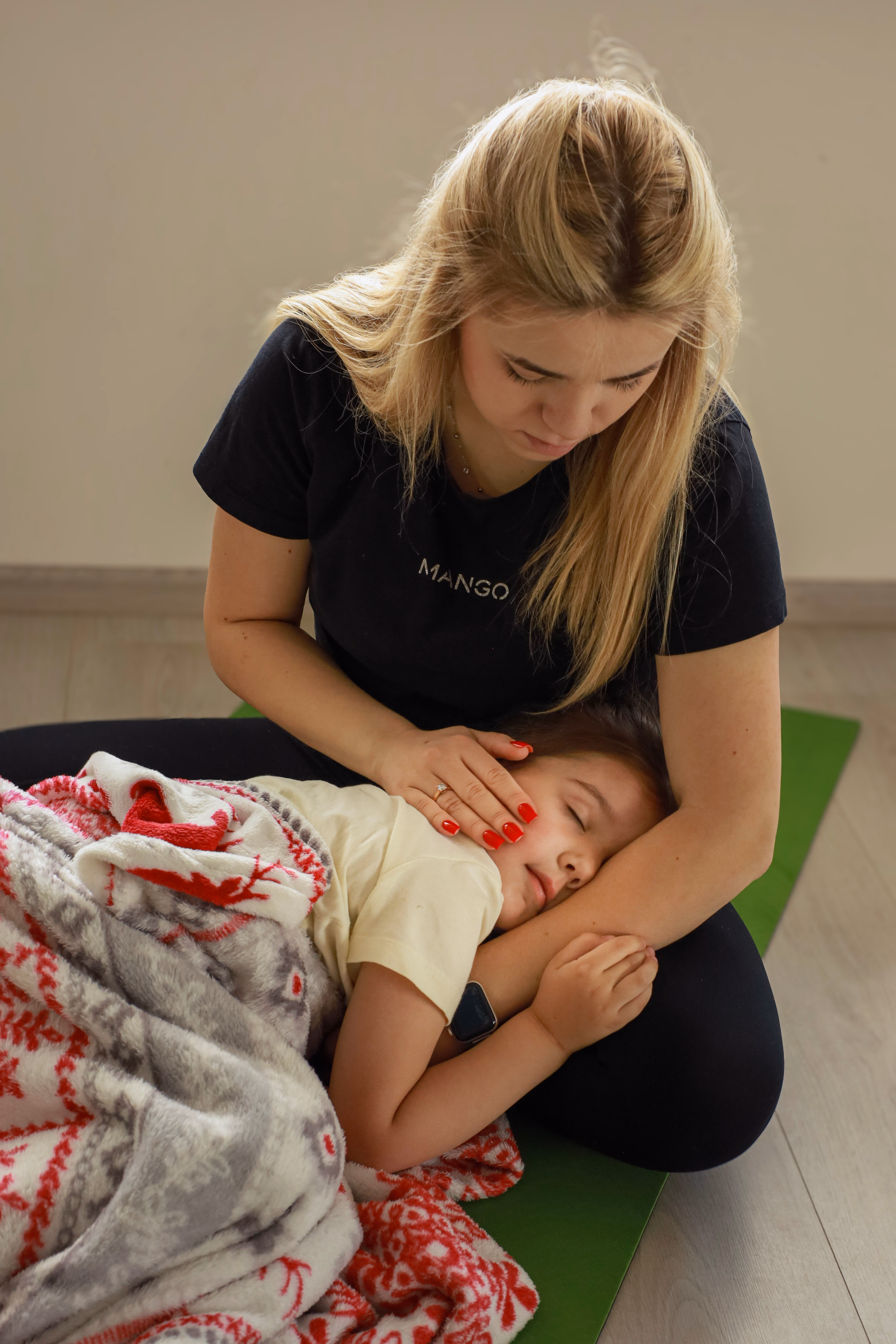 Мама тримає сплячу дитину на килимку після заняття