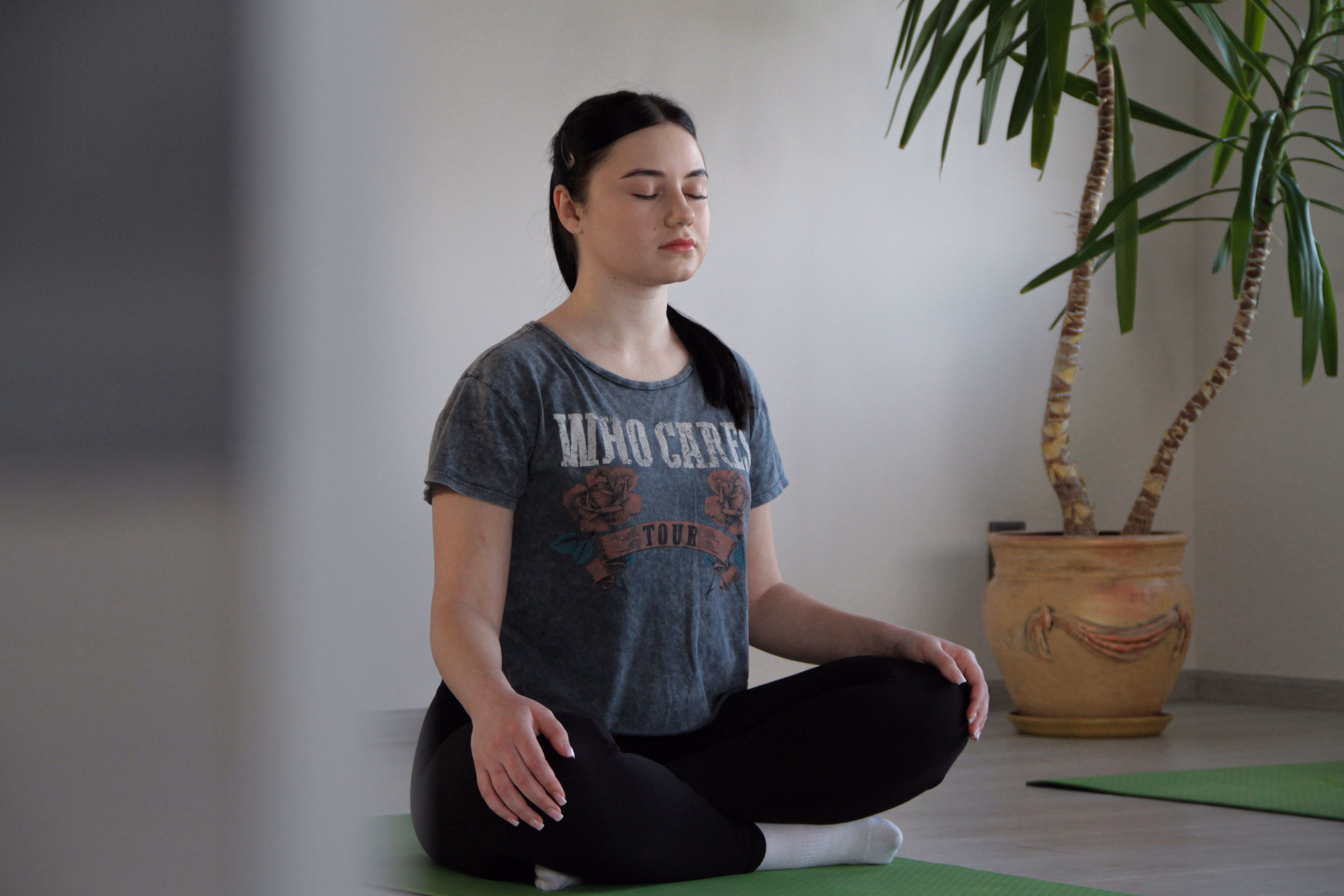 Учениця медитує в позі лотоса із заплющеними очима